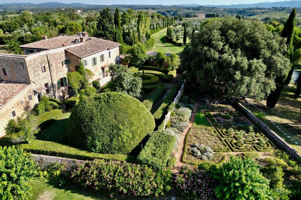 Casa de campo italiana com jardim formal e paisagem toscana ao fundo