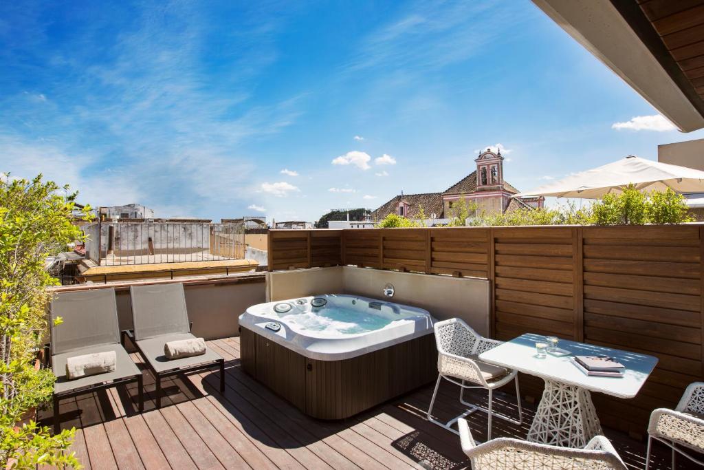 Terraço do quarto do Hotel Casa 1800 Sevilla, com jacuzzi ao centro, cadeiras e uma mesa.