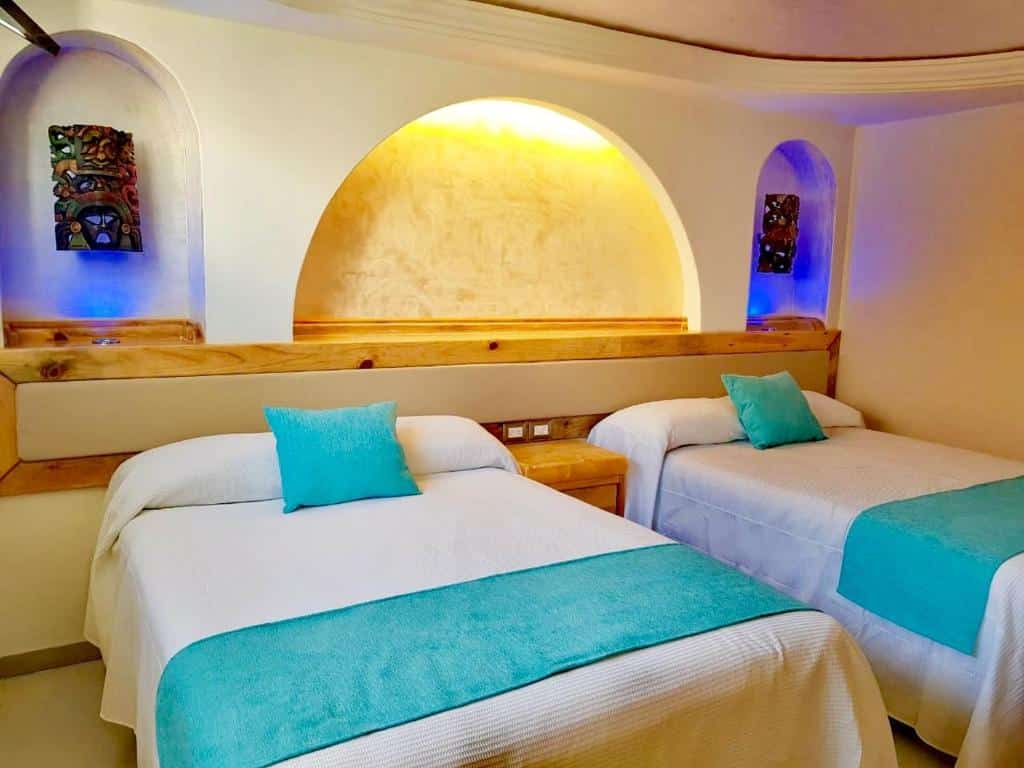 Quarto no Hotel Blue Star Cancun com cama de casal e cama de solteiro, alguns elementos decorativos, em azul e branco