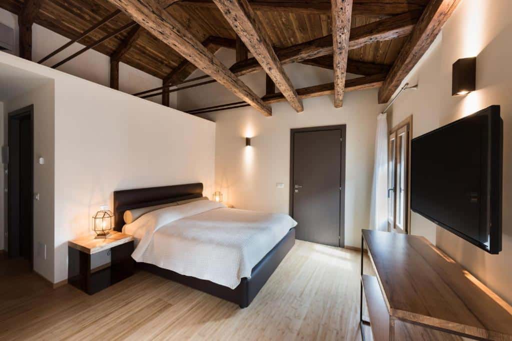 Quarto de hotel rústico com teto de madeira, cama de casal e móveis em tons escuros