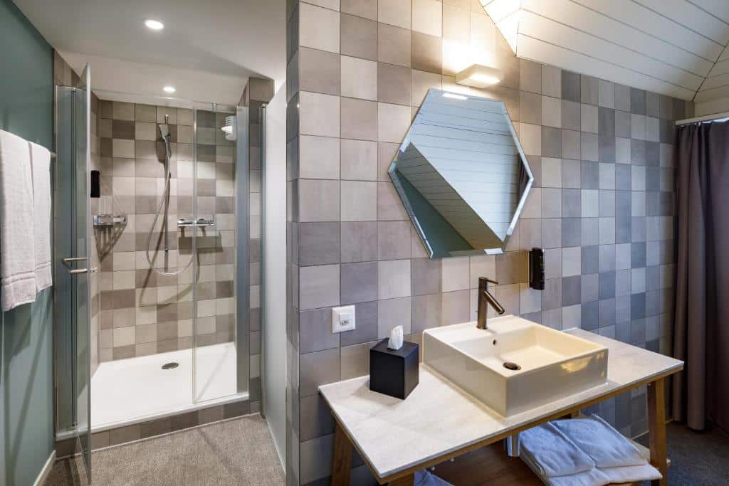 Casa de banho moderna no Hotel Münzgasse, com lavatório, espelho hexagonal e cabine de duche.