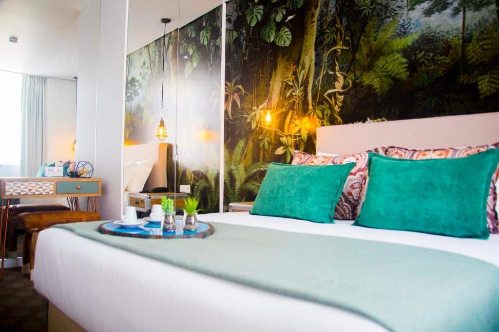 Quarto do Thomar Boutique Hotel com cama de casal, almofadas coloridas e papel de parede com motivos de natureza