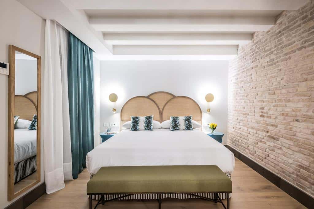 Quarto do Hotel Casa de Indias By Intur com cama de casal, banco aos pés e janela com cortina.