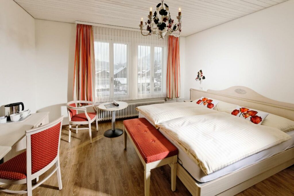 Quarto do Hotel Beausite com cama de casal, secretária e mesa redonda.