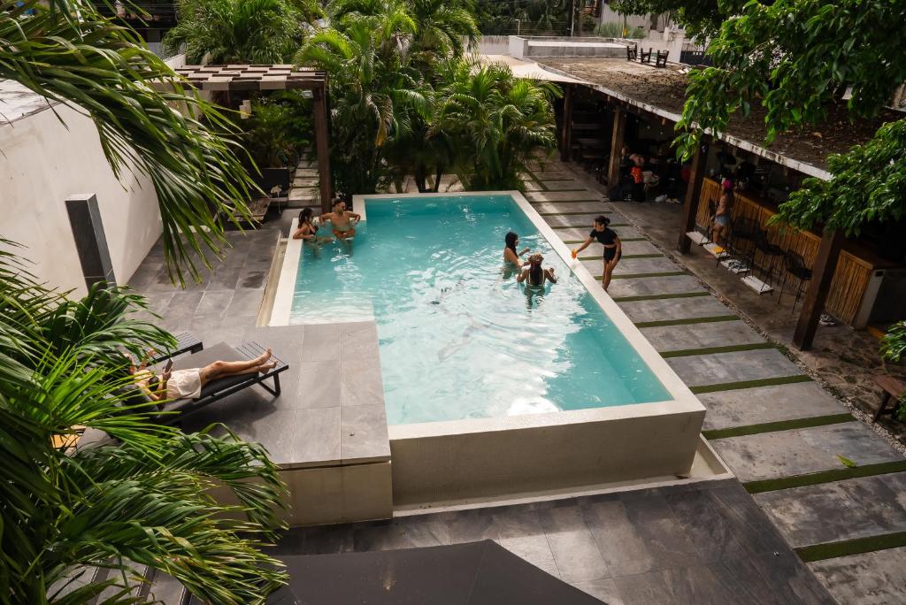 Piscina retangular numa área de lazer com pessoas a divertir-se e um hóspede a relaxar numa espreguiçadeira, no SUUT Hostal Boutique.