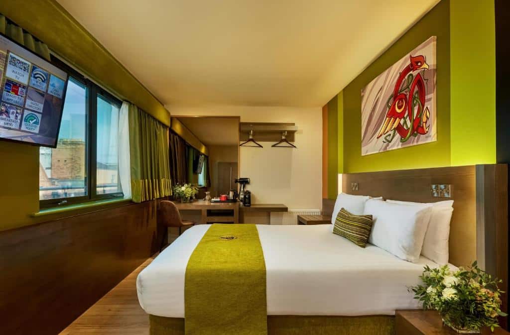 Quarto do Temple Bar Inn com decoração minimalista em tons de verde e castanho, com parede de arte e janela ampla com vista para a cidade.