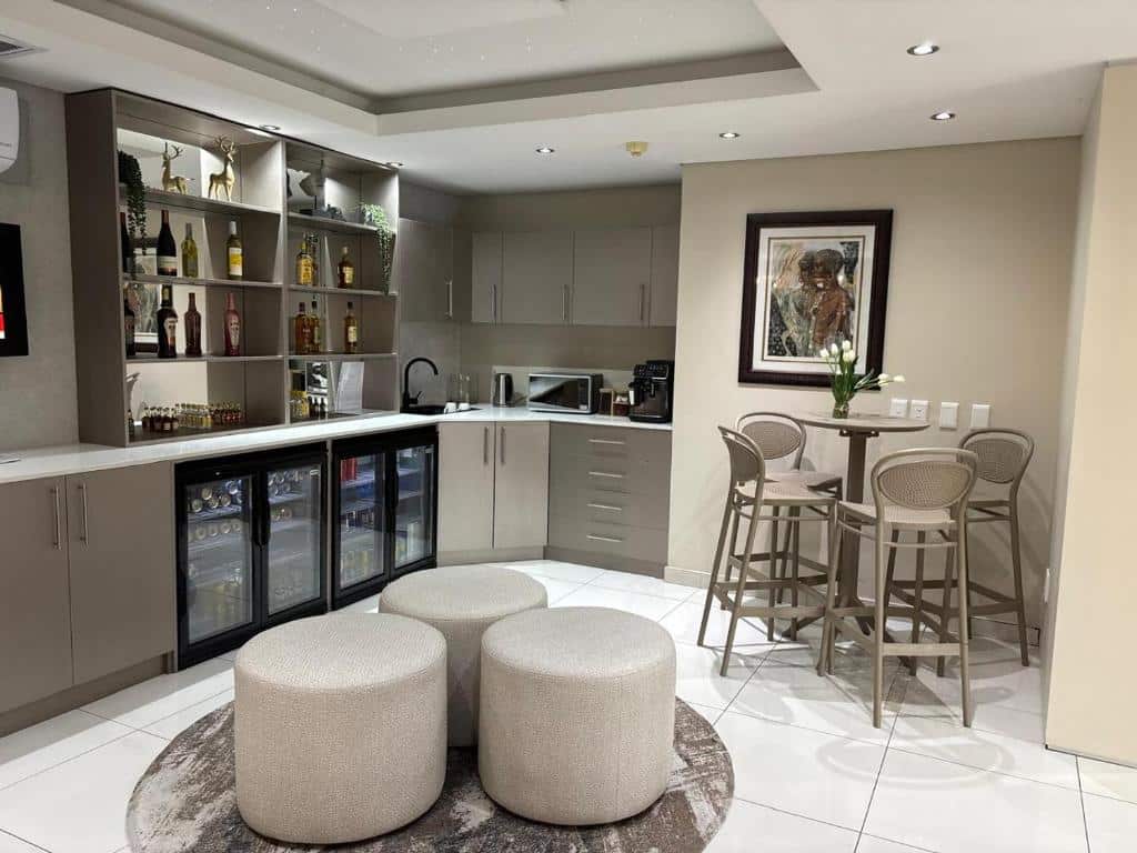 Cozinha moderna e zona de bar com garrafas, uma pequena mesa de refeições e bancos numa acomodação do Atlantic Affair Boutique Hotel.