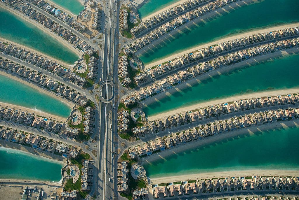 Vista aérea da Palm Jumeirah, com as suas frondes residenciais simétricas e canais de água azul-turquesa.