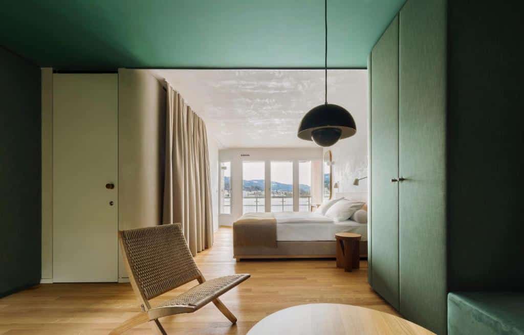 Quarto do HERMITAGE Lake Lucerne, com guarda-roupa verde-escuro e varanda com vista para o lago.