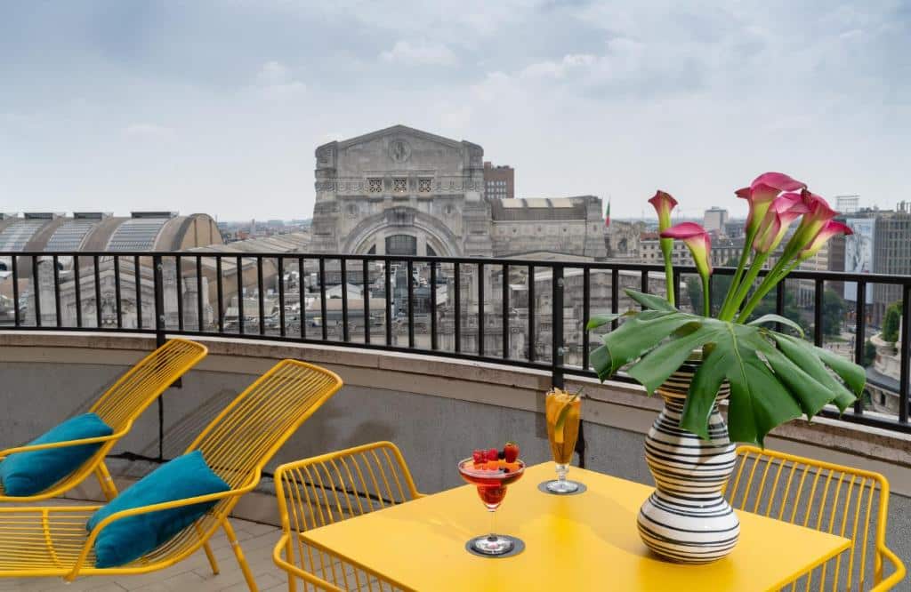 Terraço com espreguiçadeiras amarelas e vista sobre um monumento no NYX Hotel Milan by Leonardo Hotels