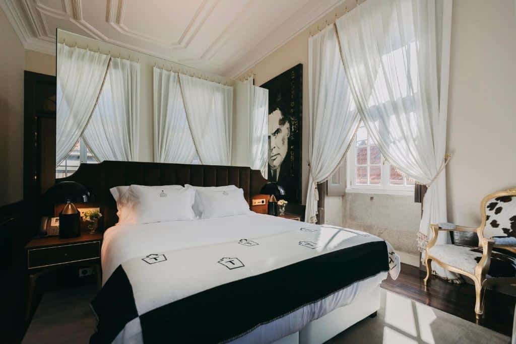 Quarto do Torel Palace Porto com cama de casal, mesinhas de cabeceira com candeeiro e uma cadeira.