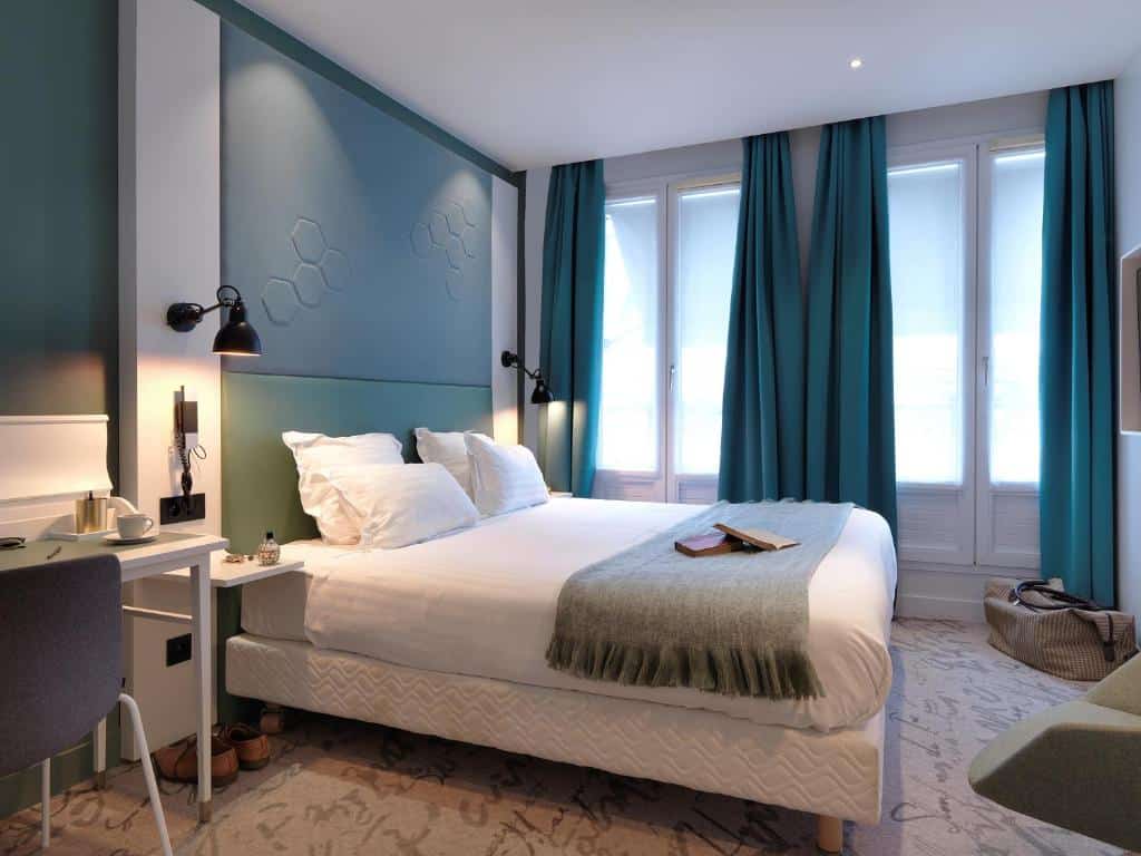 Quarto simples com cortinas e paredes azuis no Hôtel Vendome Saint-Germain, um dos hotéis onde ficar em Paris
