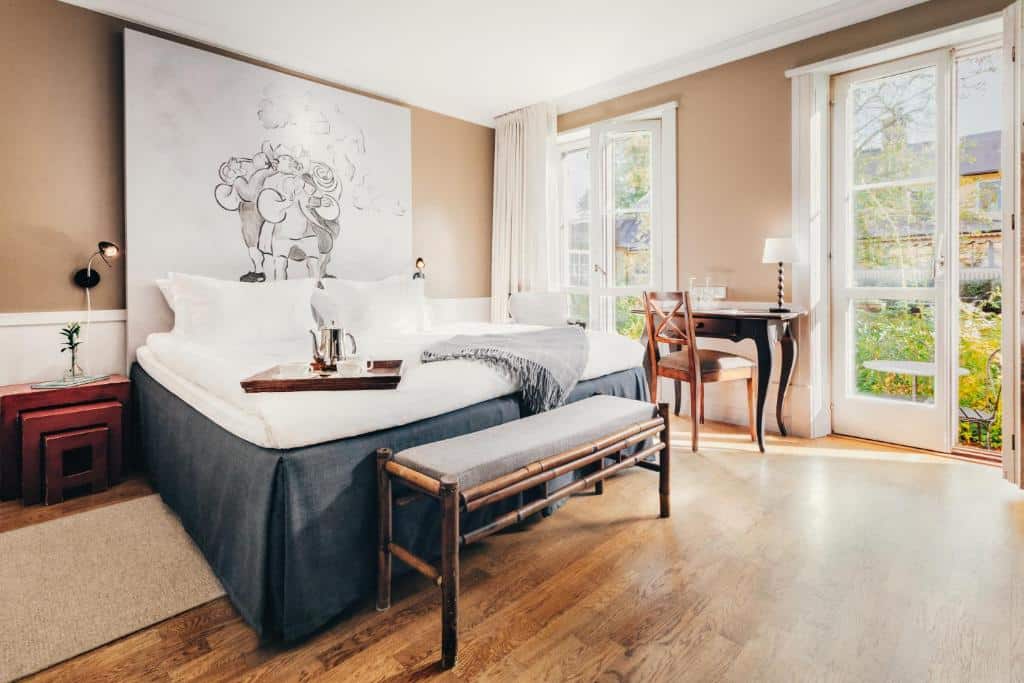 Quarto do Stallmästaregården Hotel com cama de casal, cómoda, mesa com cadeira e banco estofado.