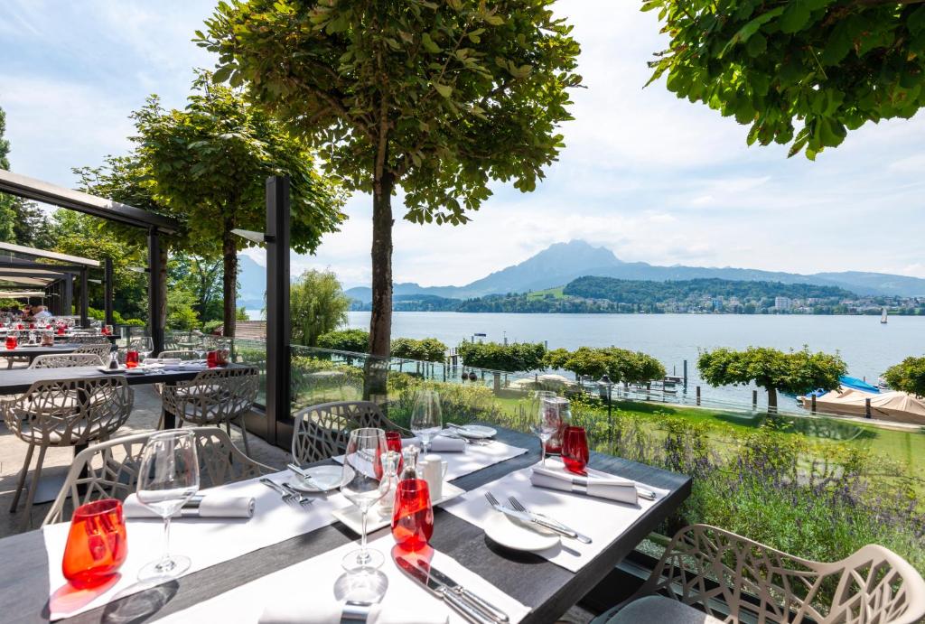 Restaurante ao ar livre no HERMITAGE Lake Lucerne, com vista para o jardim, o lago e as montanhas.