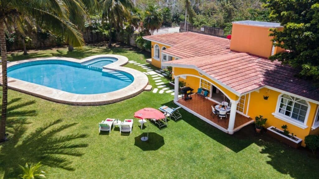Casa amarela com piscina ampla e relvado extenso no Orchid's House