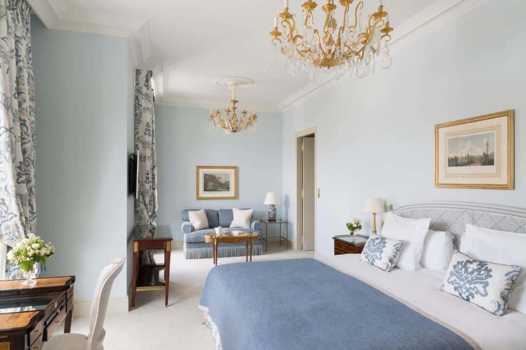 Quarto elegante do Le Bristol Paris - an Oetker Collection Hotel com decoração em azul e branco, uma cama de casal, área de estar, lustres e arte emoldurada nas paredes.