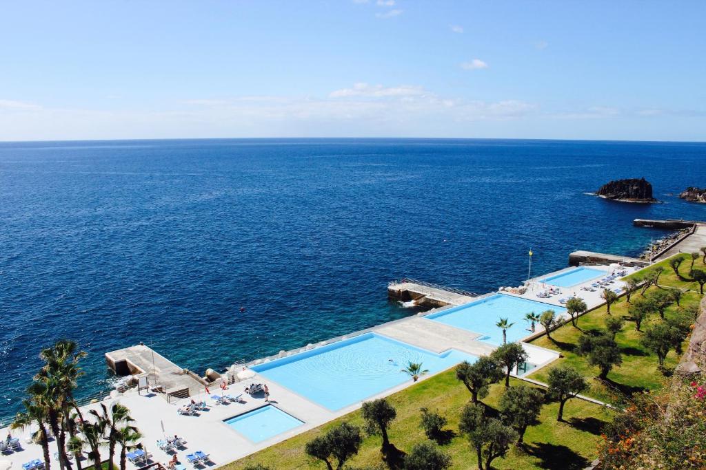 Vista aérea das piscinas do VidaMar Resort Hotel Madeira, com o mar ao fundo.