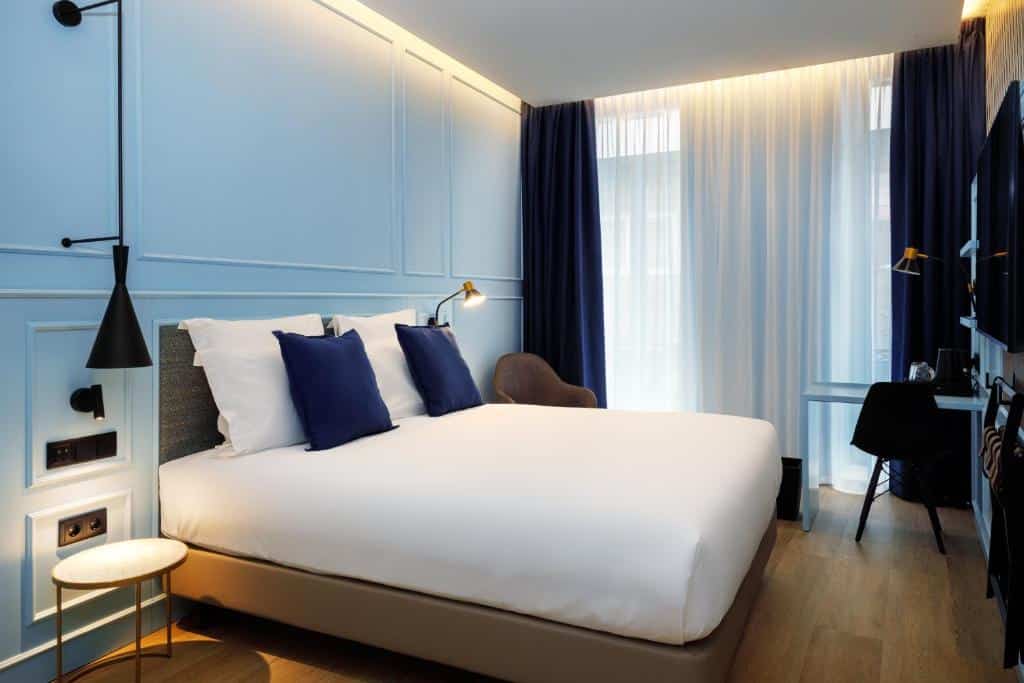 Quarto do Mercure Porto Centro Aliados com cama de casal e uma pequena secretária com cadeira.