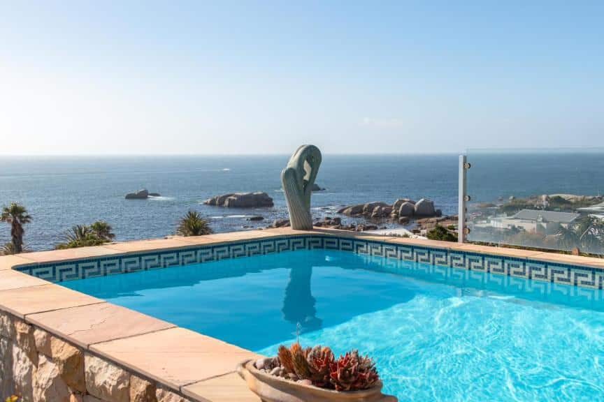 Piscina azul clara com uma estátua de golfinho no Ocean View House, com vista para o oceano e a costa.