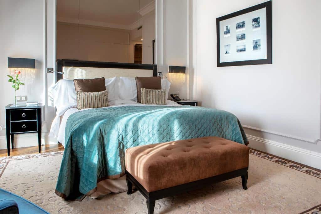 Quarto do InterContinental Porto – Palácio das Cardosas com cama de casal, mesinhas de cabeceira e banco estofado aos pés.