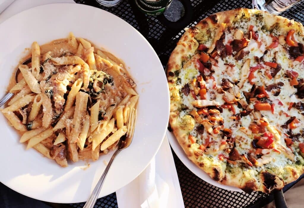 Pratos de massa e pizza numa mesa, a ilustrar opções comuns nos restaurantes de Toronto