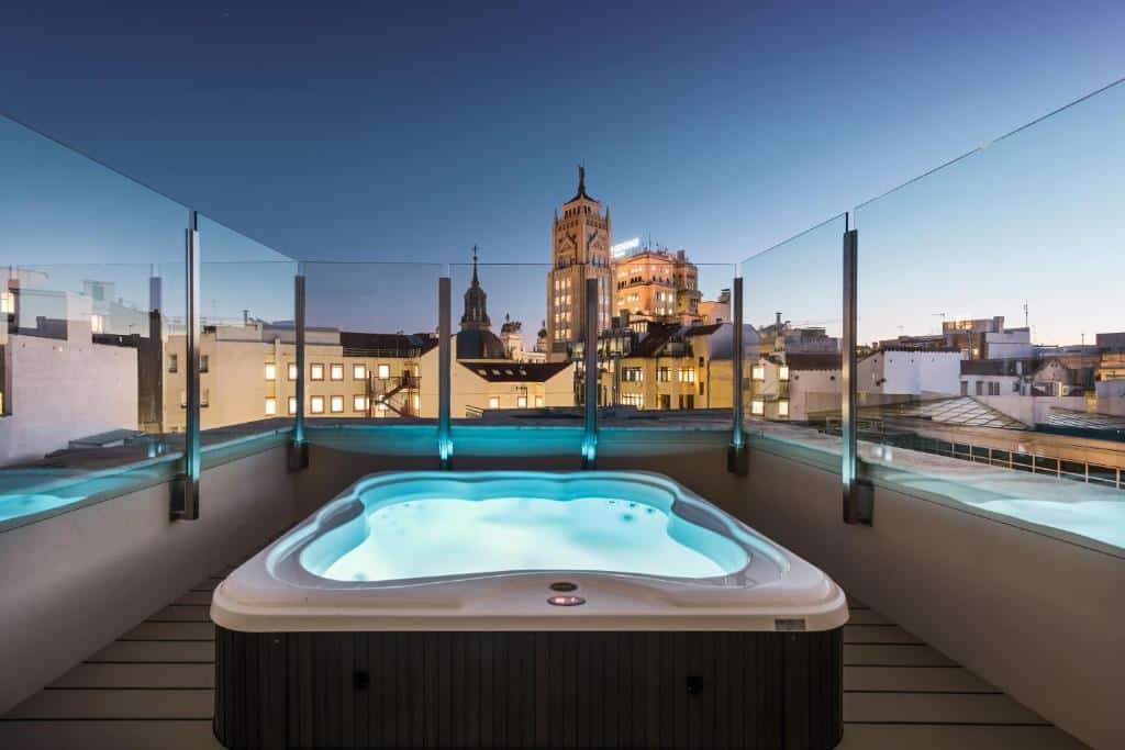 Banheira de hidromassagem no terraço do Catalonia Gran Vía Madrid. O local tem vista da cidade e proteção de vidro à volta.