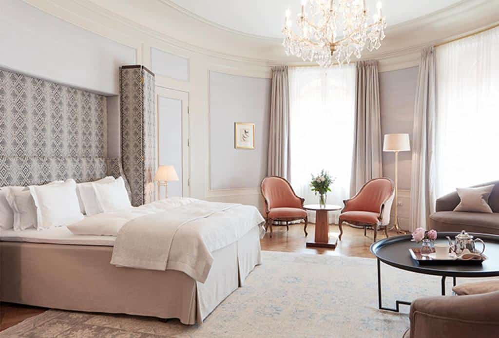 Quarto do Hotel Diplomat Stockholm com mesa redonda, cama de casal e duas poltronas.