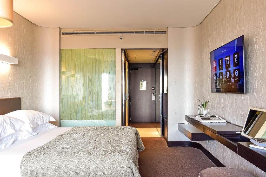 Quarto do Porto Palácio Hotel by The Editory com cama de casal e uma mesa com televisão em frente.