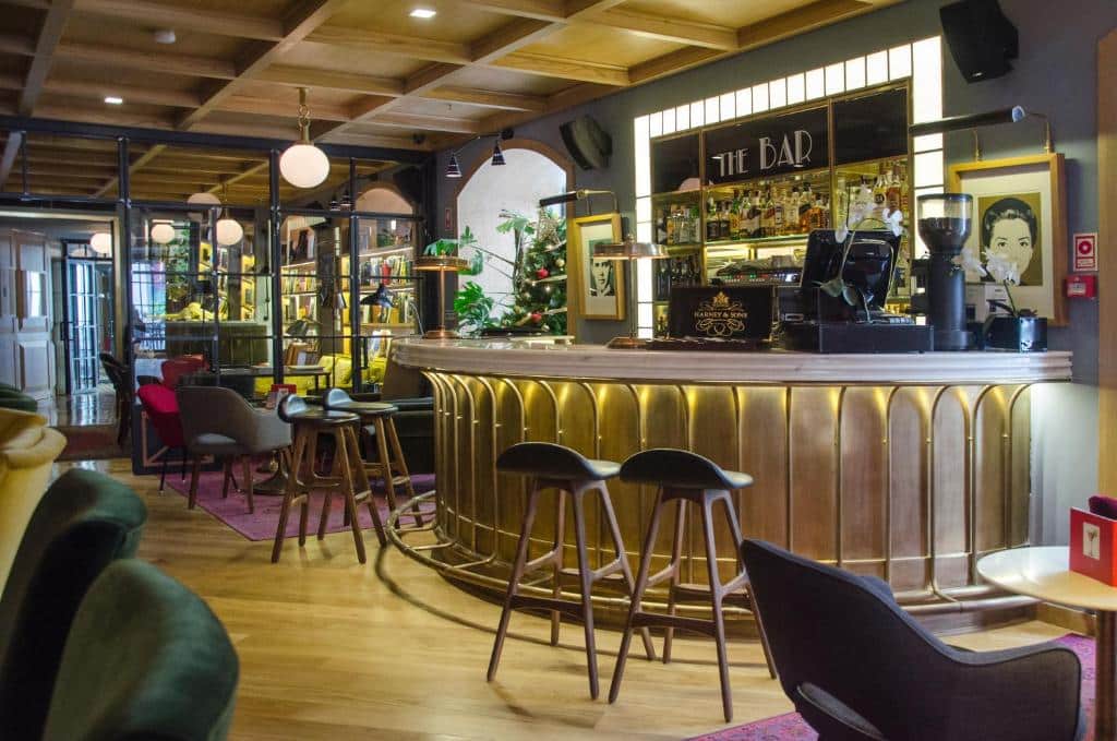 Bar do Browns Central Hotel com decoração de época em estilo noir, poltronas estofadas, bancos e candeeiros redondos.