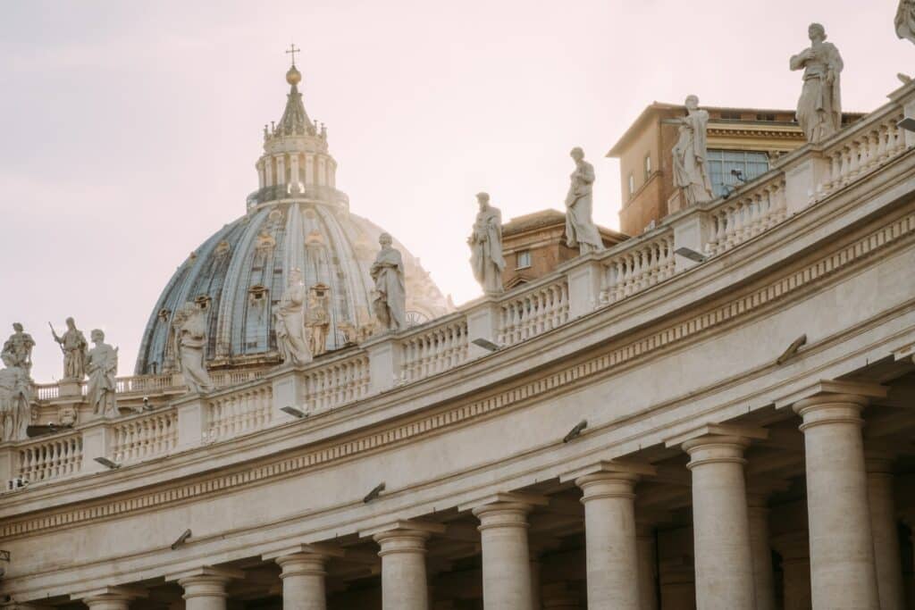 fachada da Basílica de São Pedro, no Vaticano, com colunas romanas, esculturas dos apóstolos e cúpula muito trabalhada com pormenores dourados