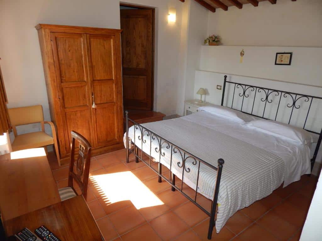 Quarto acolhedor com cama de casal, roupeiro de madeira e secretária