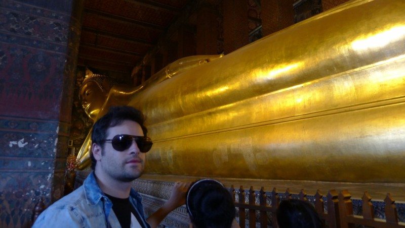 Grande estátua dourada do Buda reclinado no interior do templo Wat Pho, com iluminação suave.