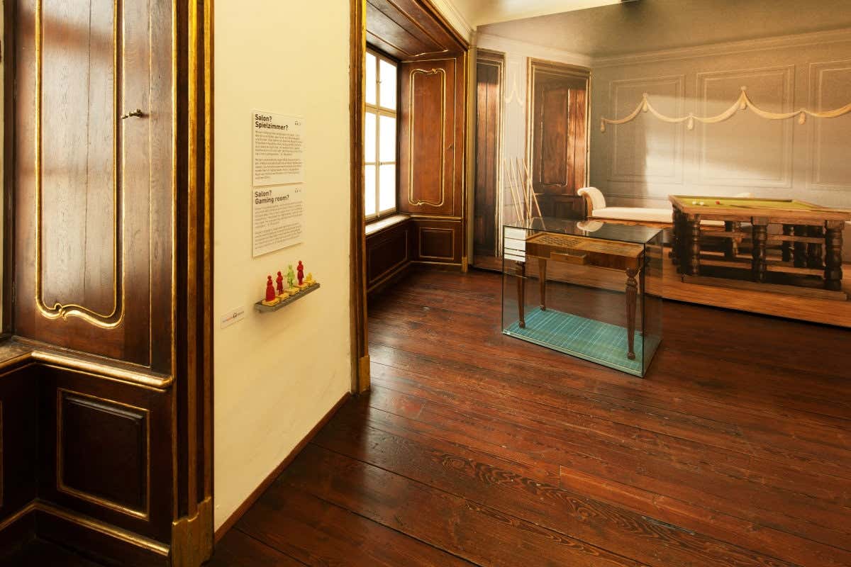 Sala da Mozarthaus, com painéis de madeira, mobiliário de época e vitrinas, sobre soalho de madeira polida.