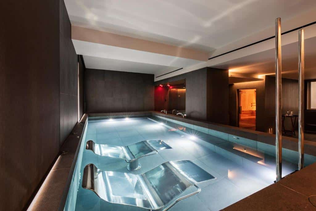 Piscina interior do Eurostars Aliados com duas cadeiras de metal dentro de água.