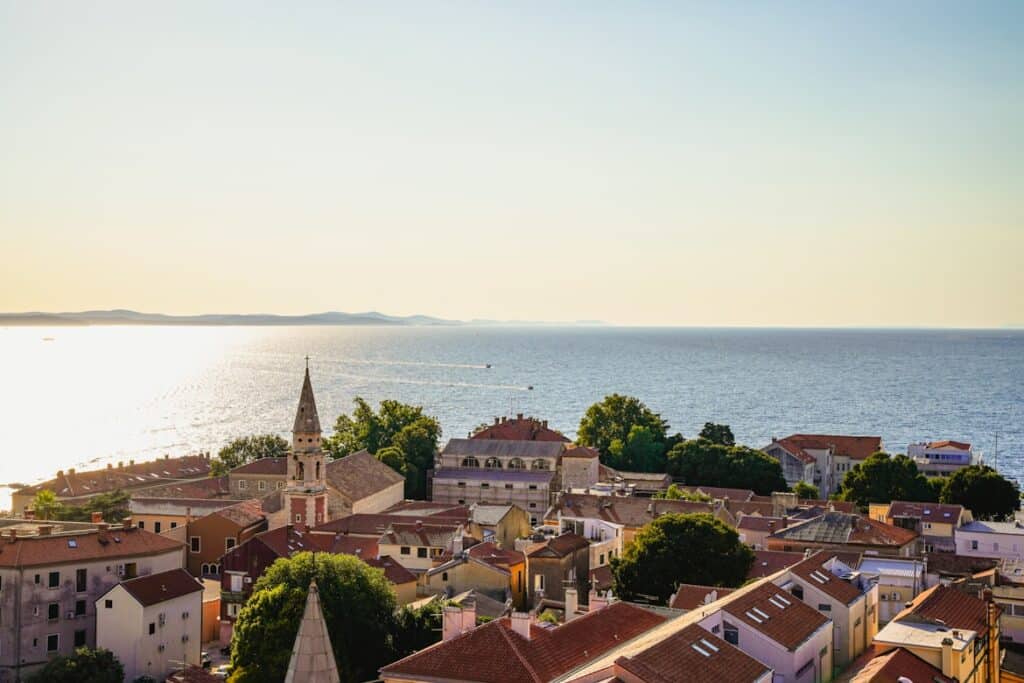Vista aérea de cidade costeira com telhados vermelhos e mar azul calmo ao fundo, Zadar, na Croácia