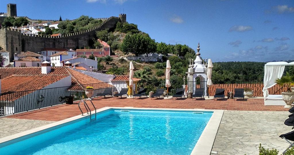 Piscina do Hotel Real d'Óbidos num terraço na cobertura, com espreguiçadeiras, guarda-sóis e vista para o castelo