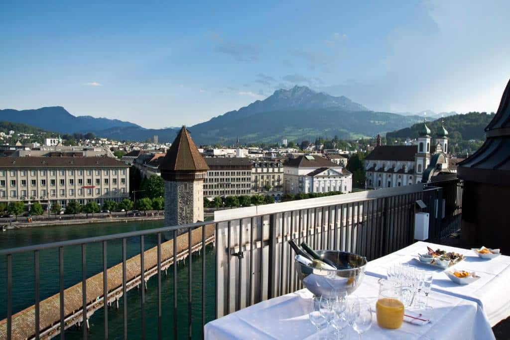 Varanda do Hotel Des Alpes, com mesa posta e vista para o lago e a cidade de Lucerna.