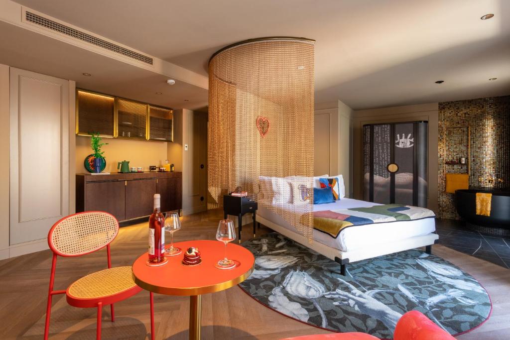 Quarto amplo do Upon Angels - Adults Only, onde, na mesma divisão, há uma cama de casal, uma cozinha compacta, um duche e uma banheira, além de uma pequena mesa redonda com vinho e copos