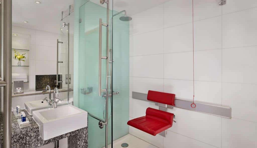 Casa de banho adaptada do Park Plaza County Hall London com cordão de emergência, uma cadeira no interior do duche e lavatório mais baixo.