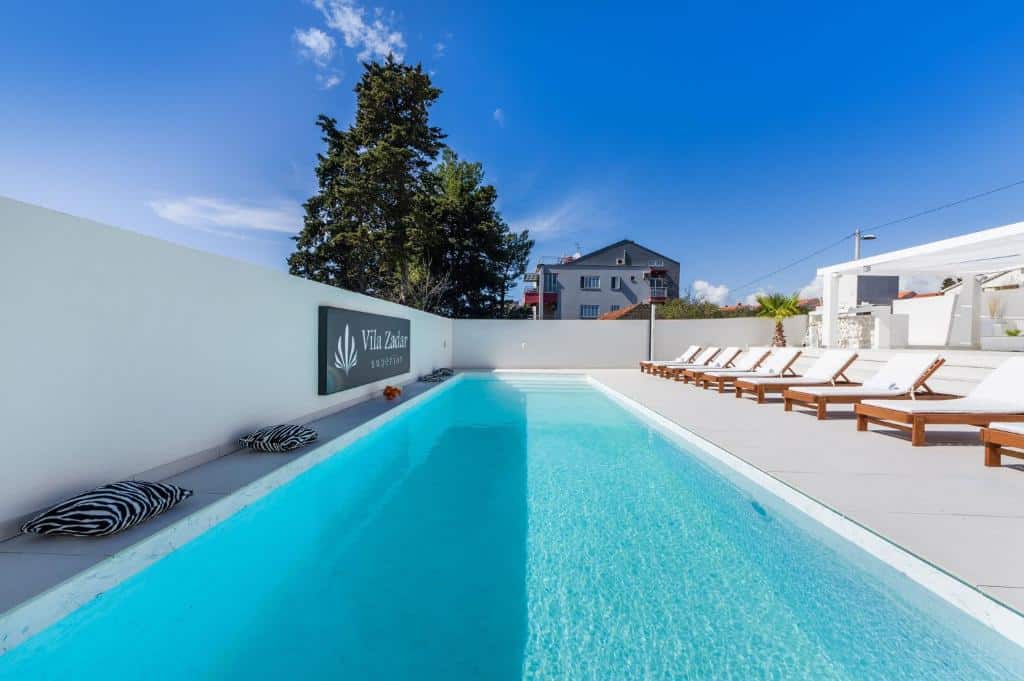 Piscina retangular azul-turquesa com espreguiçadeiras numa área exterior da Villa Zadar Superior, em Diklo