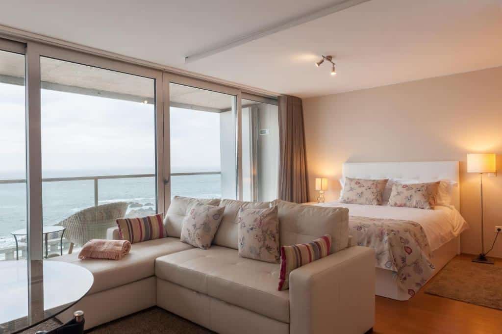 Quarto do Bartolomeu Beach Apartments, com cama de casal à direita e um sofá aos pés da cama.