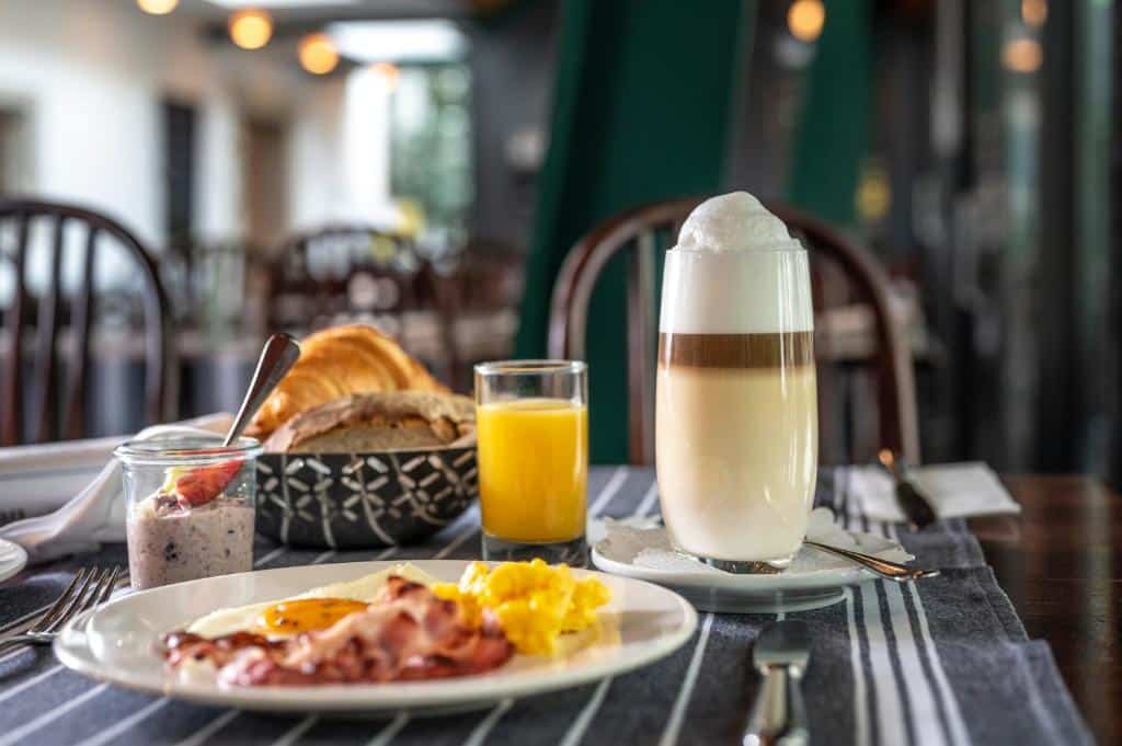 Pequeno-almoço no Hotel Hofgarten Luzern, com ovos, bacon, sumo, iogurte e cesto de pão.