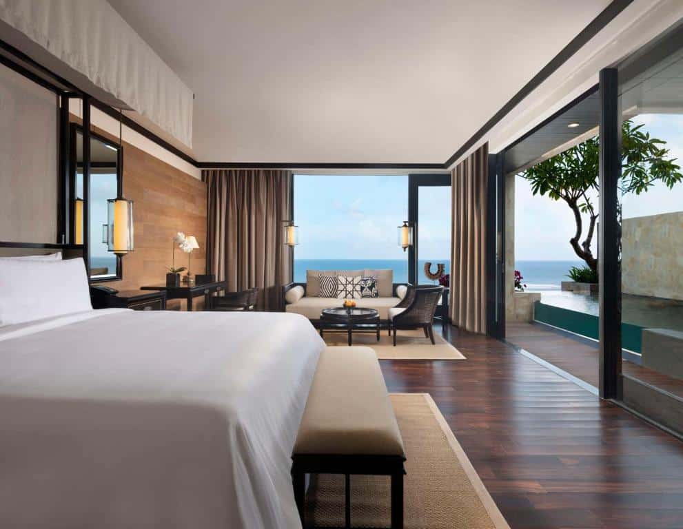 Quarto de luxo com cama grande e portas de correr abertas para uma piscina privativa com vista de mar, num resort em Bali.