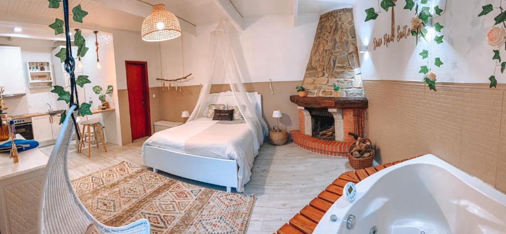 Quarto do Douro Rural Suite, com cama de casal ao centro, lareira à direita, banheira de hidromassagem ao lado e uma pequena cozinha à esquerda.