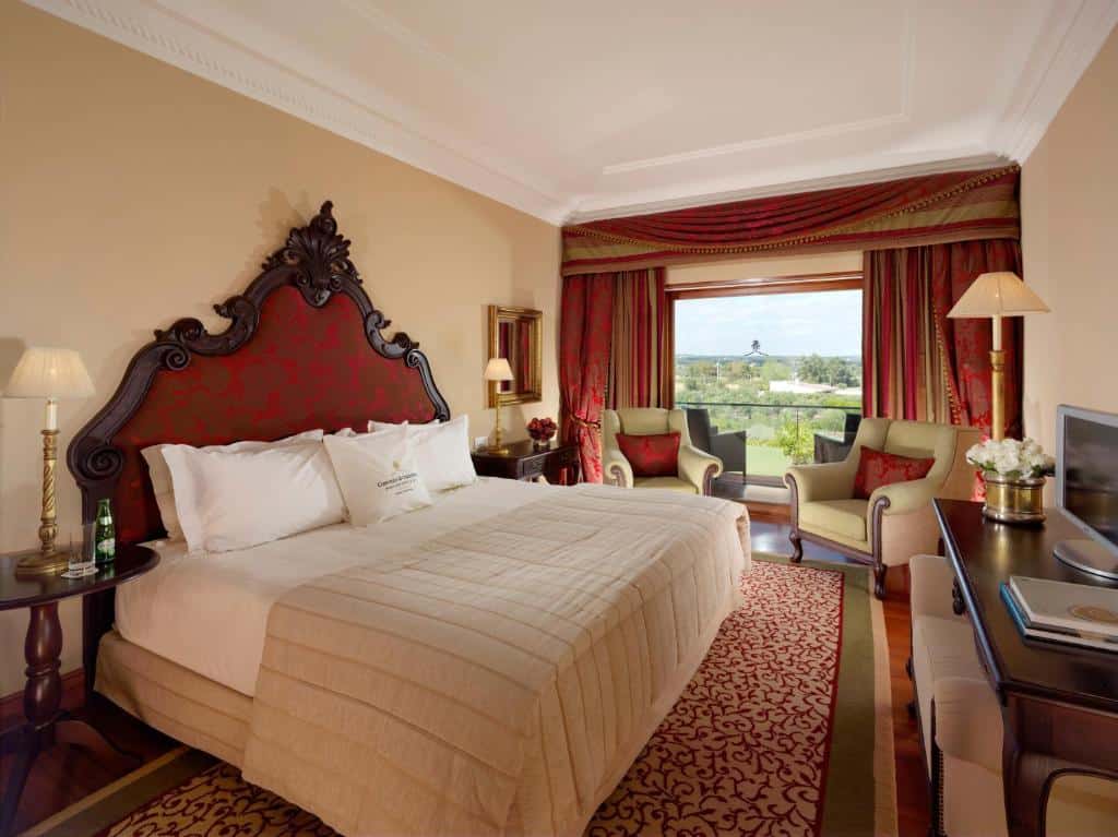 Quarto do Convento do Espinheiro com varanda com vista para a serra, poltronas e cama de casal