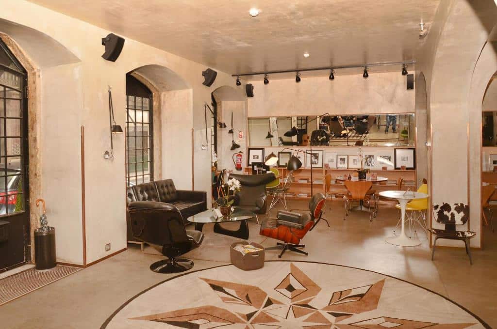 Zona de estar moderna com várias cadeiras, mesas, fotografias emolduradas em prateleiras e um grande tapete com estampa de estrelas, no Browns Downtown Hotel.