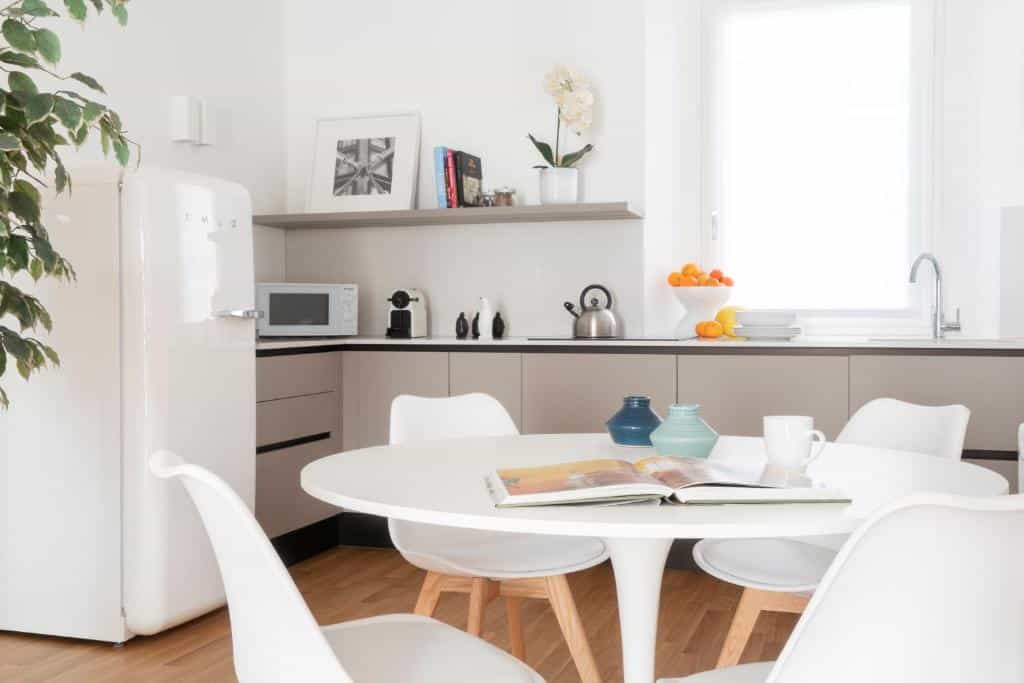 Cozinha do Brera Apartments in San Babila com uma janela com cortinas, um frigorífico, micro-ondas, máquina de café, chaleira e peças de decoração, além de uma mesa redonda de quatro lugares