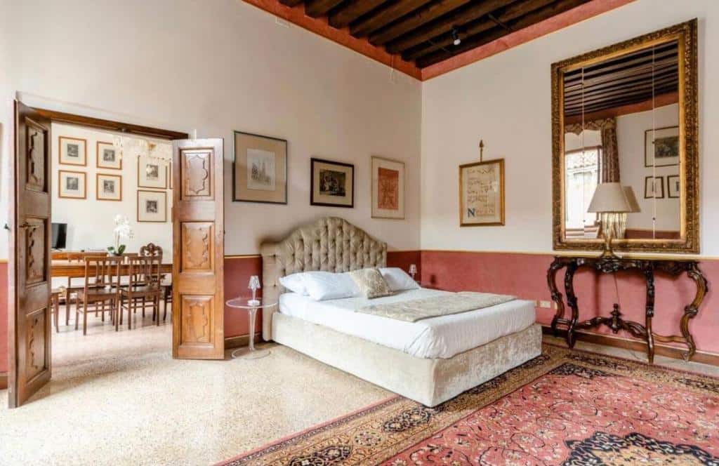 Quarto amplo e acolhedor em estilo rústico com cama de casal estofada, móveis de madeira e espelhos decorativos na parede