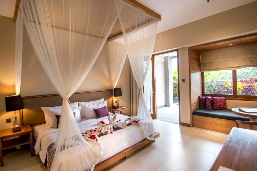 Quarto com cama de dossel, candeeiros e porta aberta para um pátio, no Ulun Ubud Resort, em Bali.