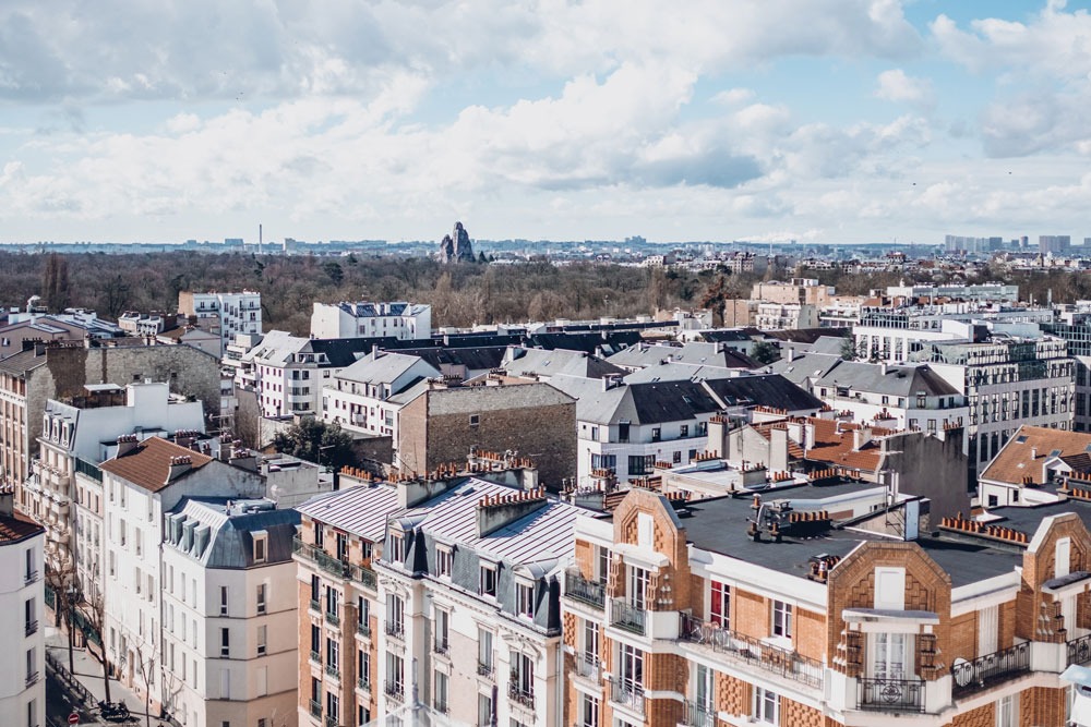 Vista panorâmica dos telhados da capital francesa, ilustrando a parte de cuidados e recomendações sobre onde ficar em Paris nos bairros periféricos